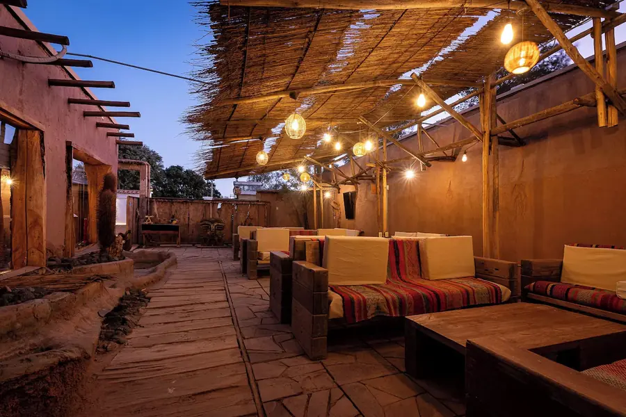 Lounge coberto de palha, com luzes acesas no fim do dia