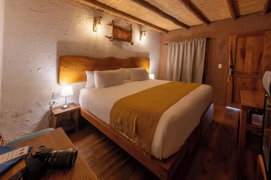 Quarto com cama king, parede de adobe e teto de bambu